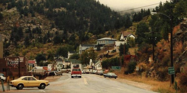 Vintage view of a small mountain town street with cars.