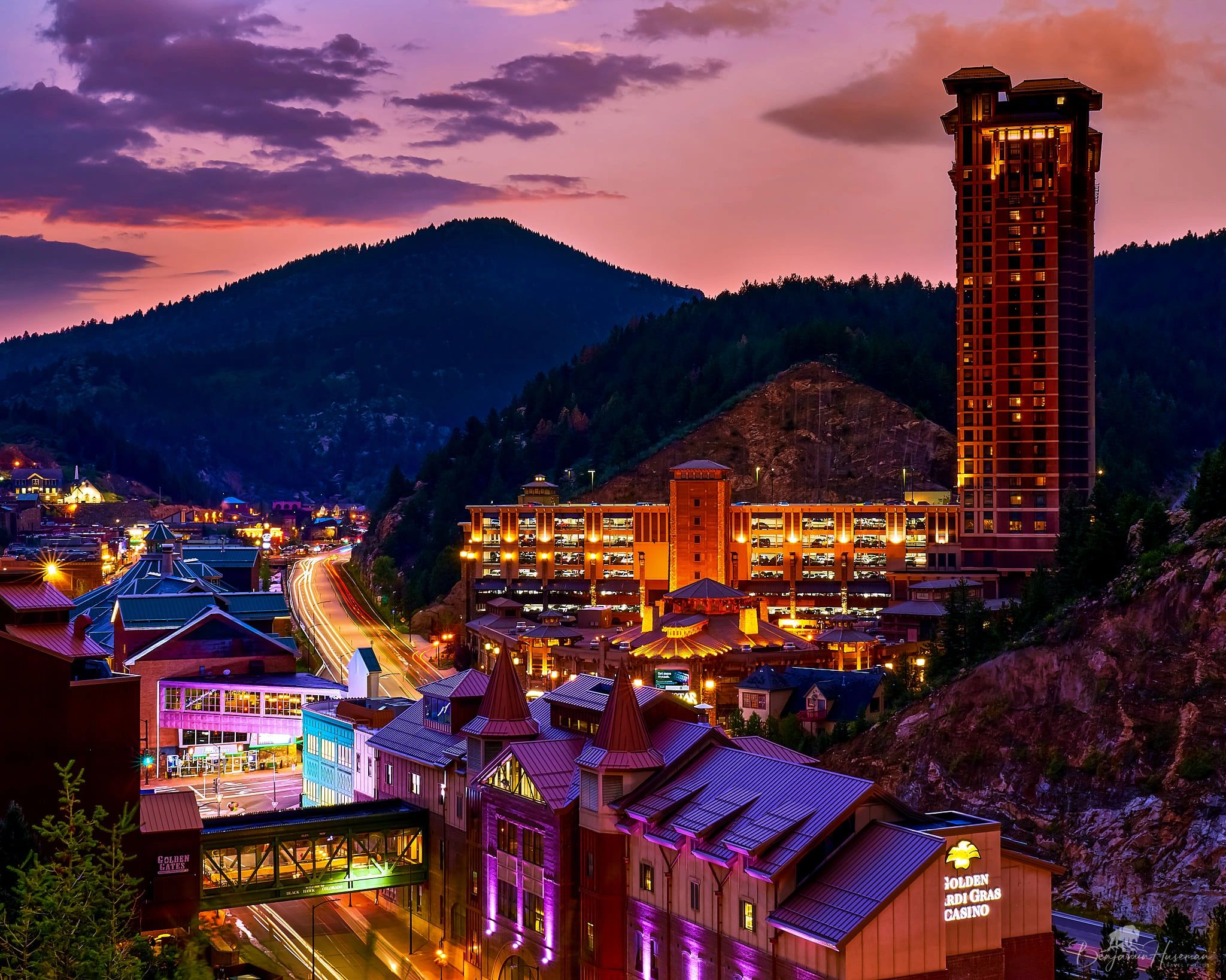 Golden Mardi Gras Casino illuminated at sunset in a mountainous town.
