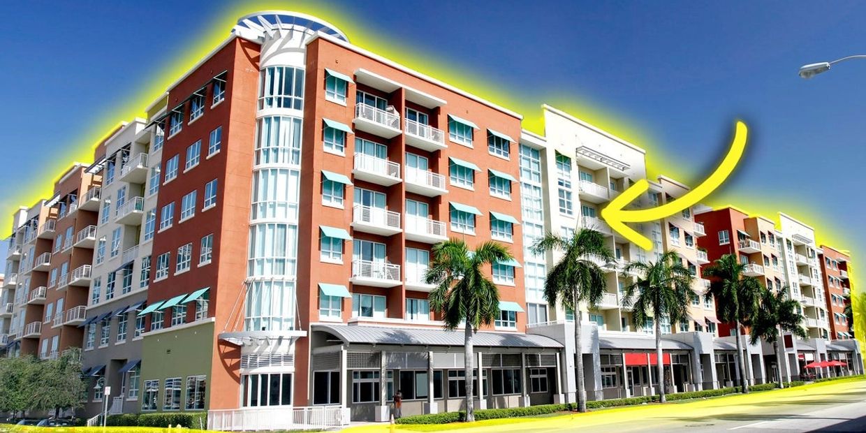 Modern apartment complex with colorful accents and palm trees.