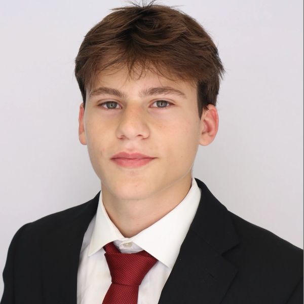 Young man in suit and red tie against a plain background.