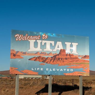 Welcome to Utah sign in desert landscape with rock formations.