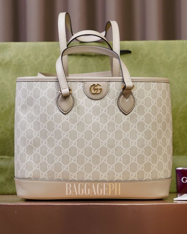Elegant beige Gucci tote bag with signature GG pattern and leather handles.