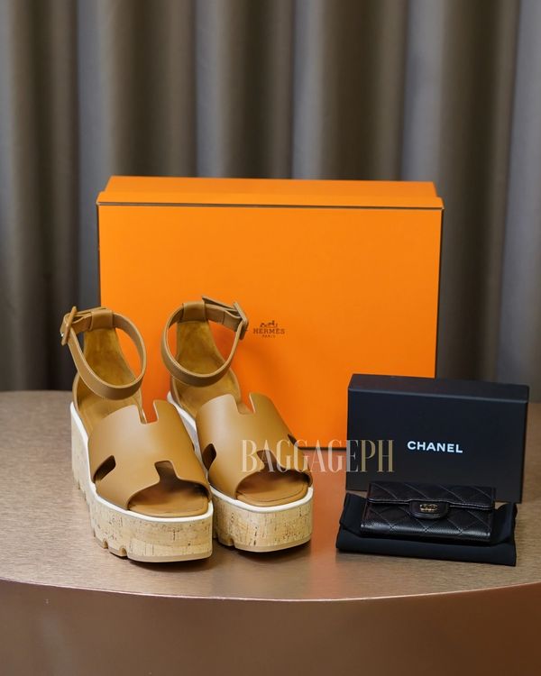 Hermes platform sandals and Chanel wallet with their boxes on a table.