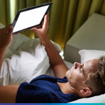 Person lying in bed using a tablet.