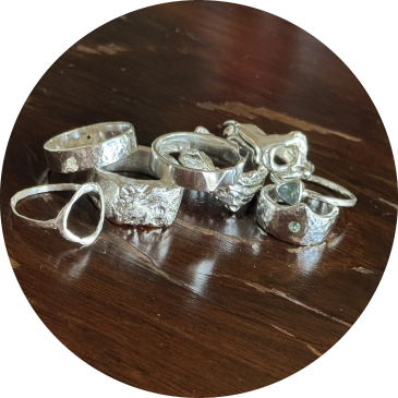 A collection of silver rings with various designs on a wooden surface.