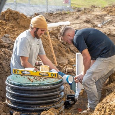 Two men working on plumbing at a construction site.