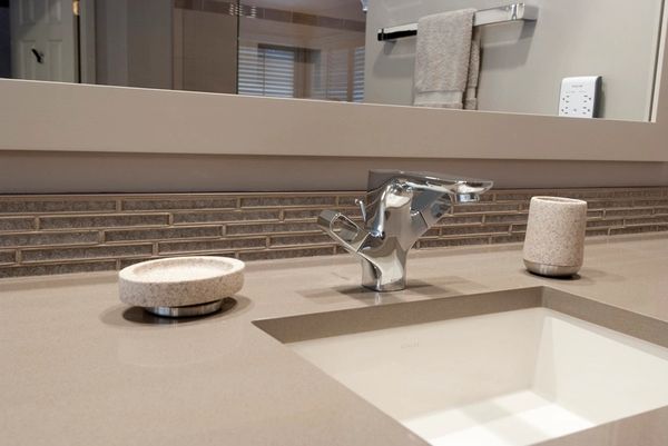 Modern bathroom sink with sleek faucet and stone accessories.
