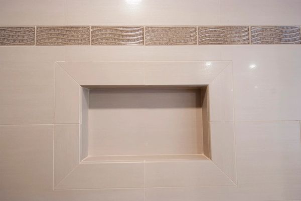 Wall niche with decorative tile border in a neutral-toned bathroom.