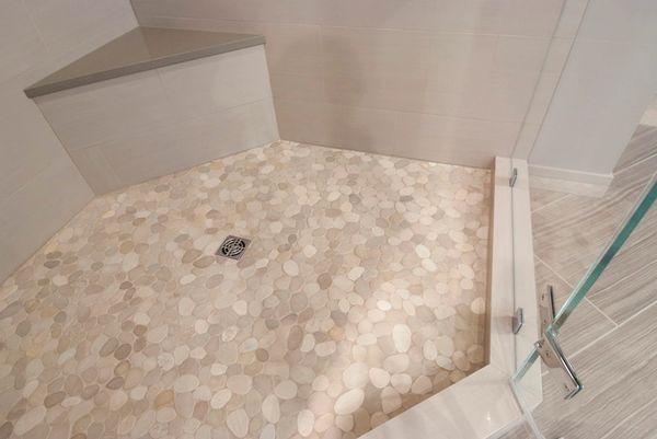 Shower floor with pebble-style tile and built-in corner seat.