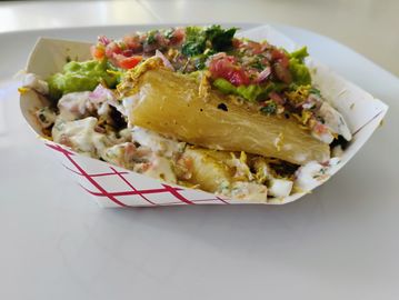 A loaded food tray with creamy sauce, guacamole, and diced vegetables.