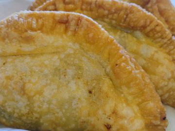 Close-up of three golden-brown fried empanadas.