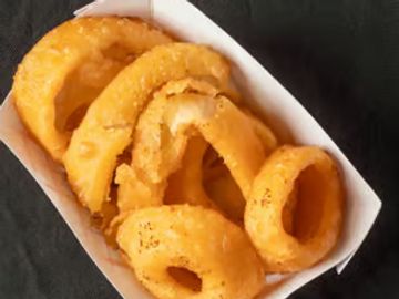 Golden crispy onion rings served in a white paper tray.