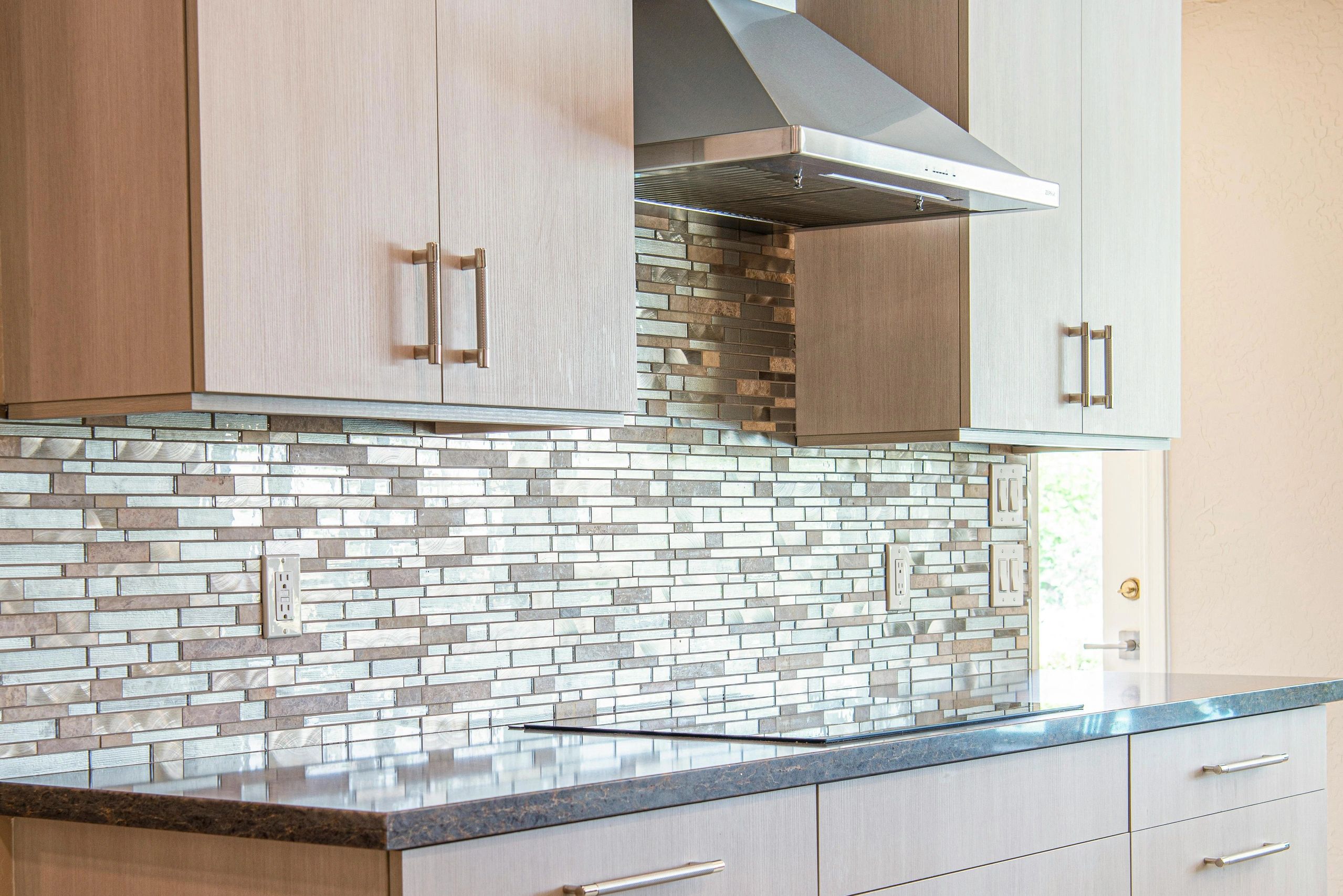 Modern kitchen backsplash with glass tiles and stainless steel range hood.