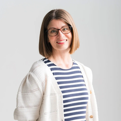 Smiling woman with glasses and striped shirt.