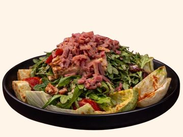A fresh salad topped with chopped bacon on a black plate.
