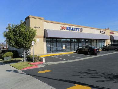 Exterior of a commercial building with a 168 Realty office and parked cars.