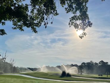Golf course sprinklers watering green fairways and a bright morning sky. View from Birdie View Villa