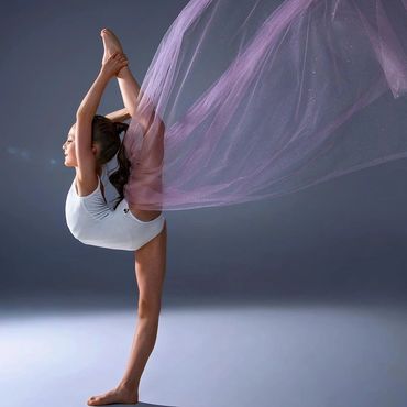 Young gymnast performing a flexible pose with flowing purple fabric.