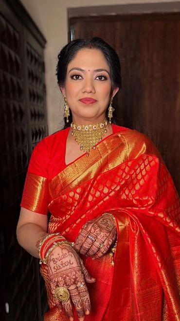 Woman in a red saree with bridal sister mehndi and gold jewelry.