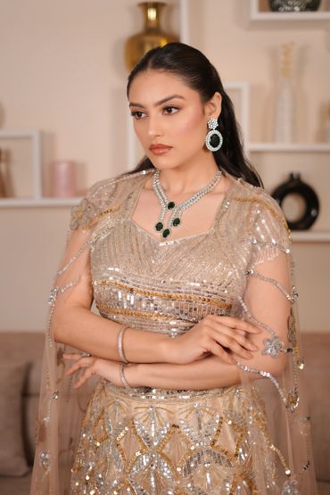 Elegant woman in a sequined dress with sparkling jewelry poses gracefully.
