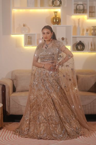 Woman in elegant golden embellished traditional attire posing indoors.