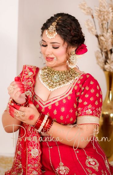 Indian bride dressed in red with traditional jewelry and floral hair accessories.