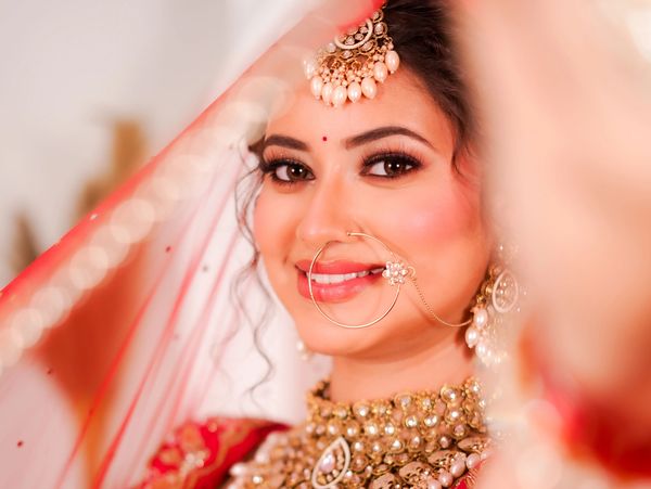 Close-up of a smiling bride in traditional Indian attire and jewelry.