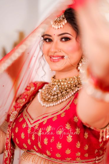 Close-up of a smiling bride in traditional Indian attire and jewelry.