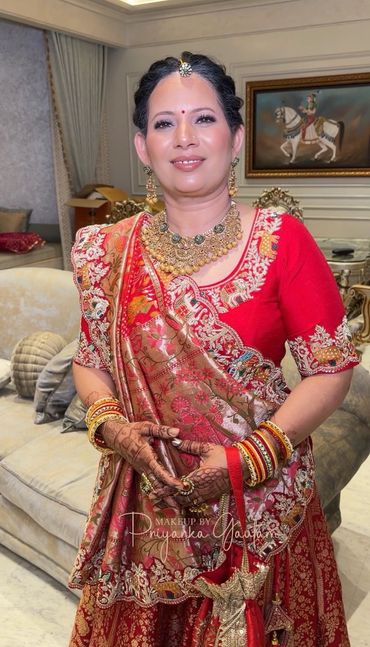 Woman in traditional red Indian attire with intricate jewelry and henna.