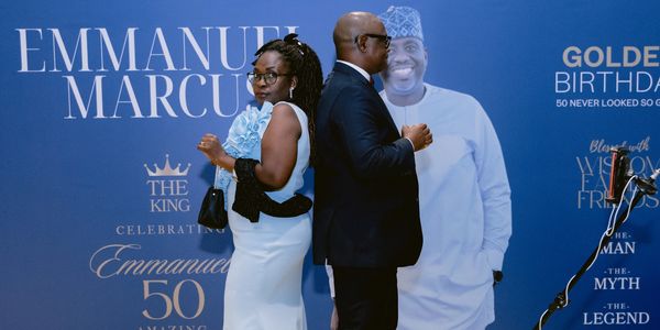 Couple posing back-to-back at Emmanuel Marcus' 50th birthday celebration.