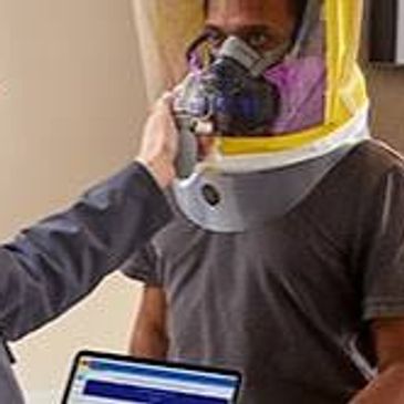 A man fitting a respirator mask for another person.