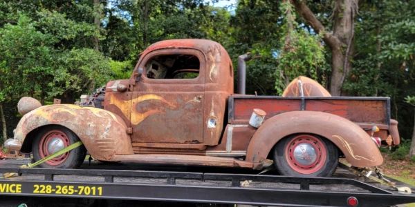 Rusty vintage pickup truck with flame decals on tow truck.