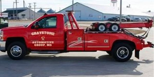 Red tow truck with automotive group branding.