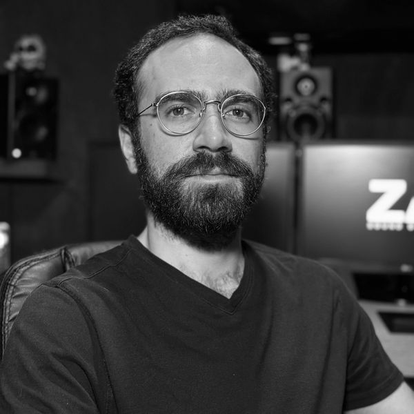 Man with glasses and beard in a studio setting.