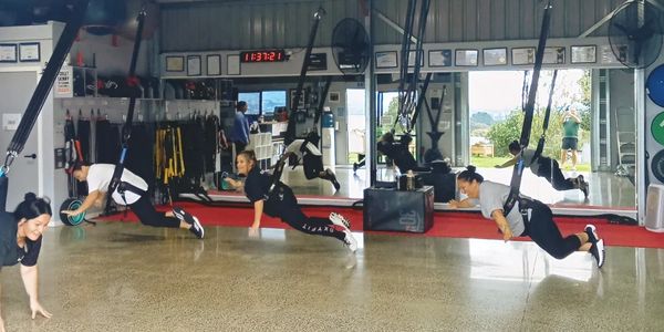 People exercising with suspension training in a gym.