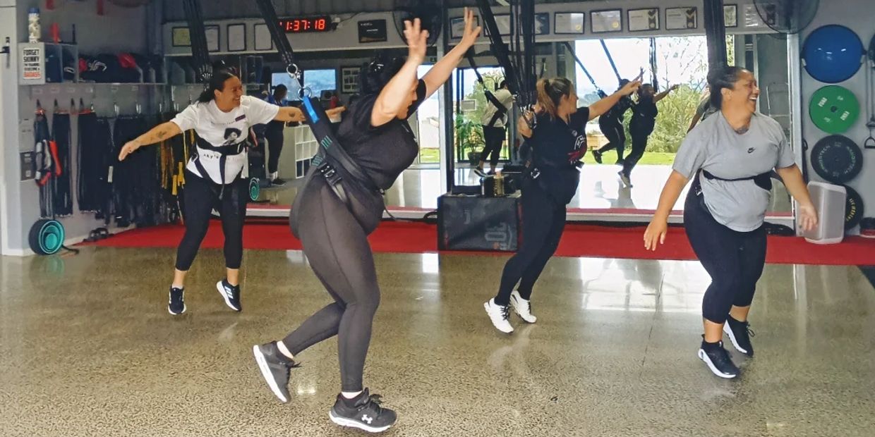 Women exercising with resistance bands in a gym.