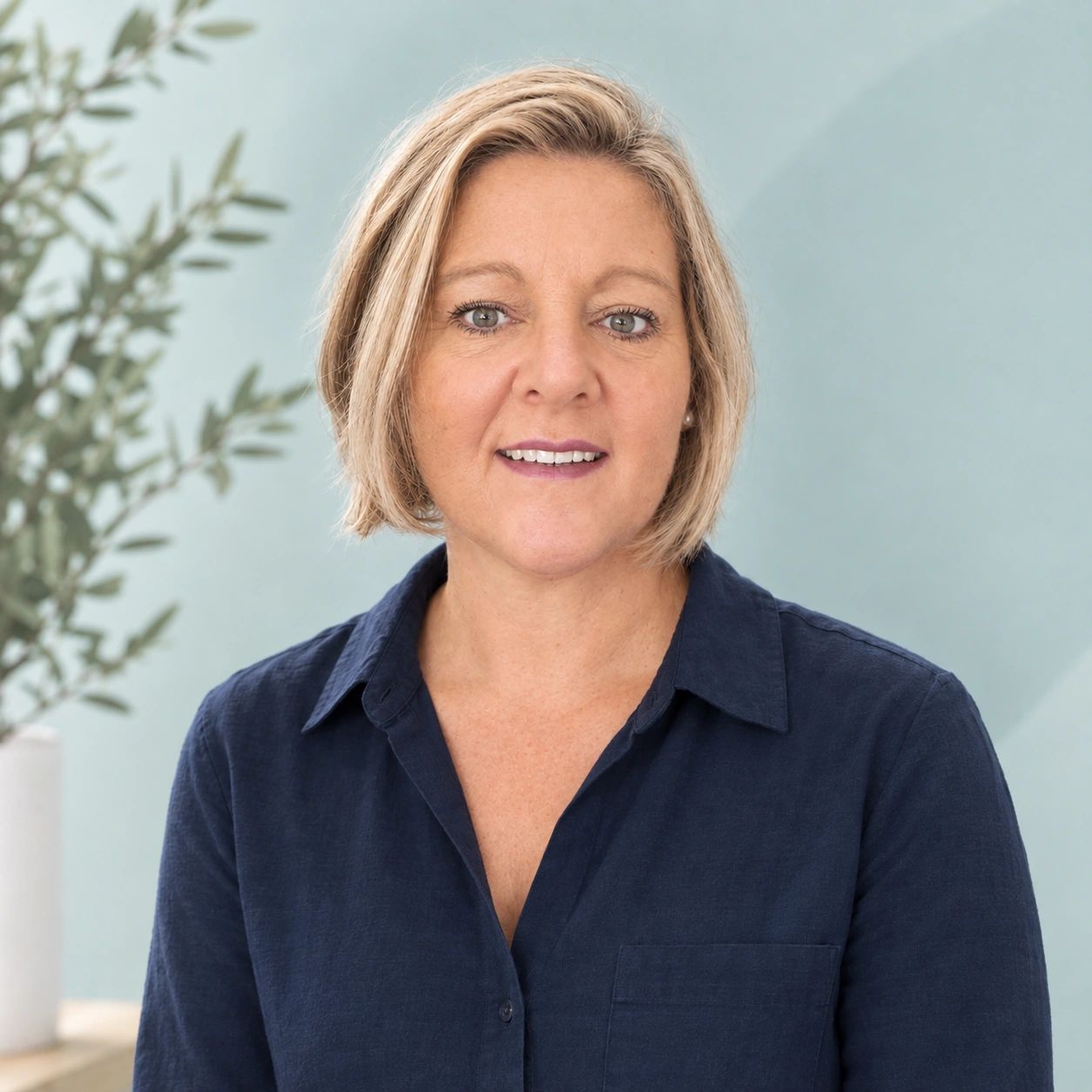 Woman with short blonde hair wearing a navy blue shirt.