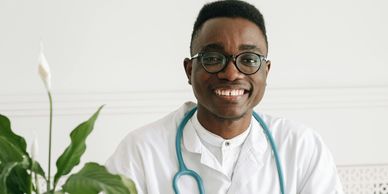Smiling male doctor wearing glasses and a stethoscope.