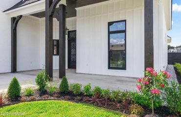 Modern white house porch with dark wooden pillars and colorful garden.