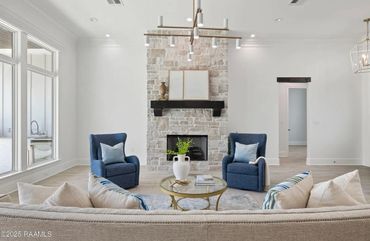 Bright modern living room with stone fireplace and blue armchairs.