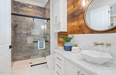 Modern bathroom with wood accent wall, glass shower, and white vanity.
