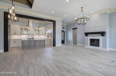 Spacious modern kitchen and living area with light gray flooring and elegant lighting fixtures.