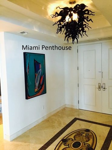 Elegant Miami penthouse entry pairs a Chihuly chandelier and Painting by Mark Biletnikoff.