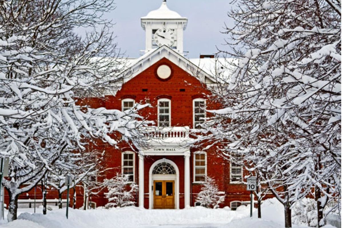 Snow-covered town hall surrounded by trees in winter.
