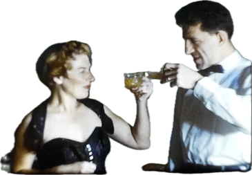 A man and woman in formal attire clink glasses in a toast.