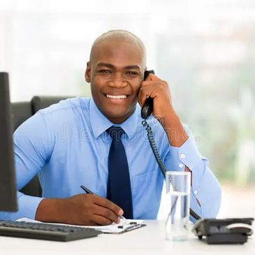 Smiling businessman talking on phone at office desk.