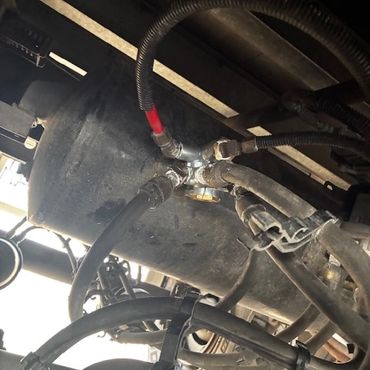 Close-up of mechanical hoses and connections under a vehicle.