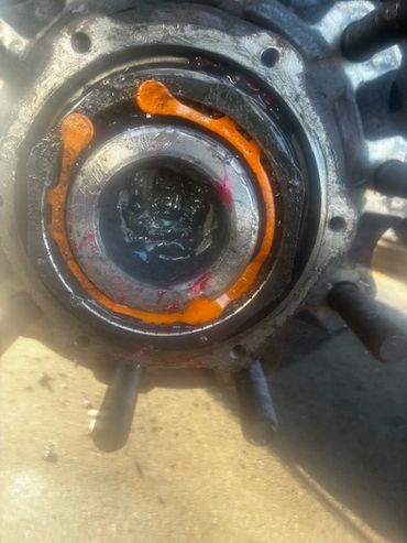 Close-up of a mechanical bearing with orange sealant inside a metal housing.