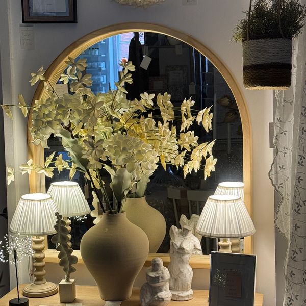 Decorative vases and lamps in front of an arched mirror.