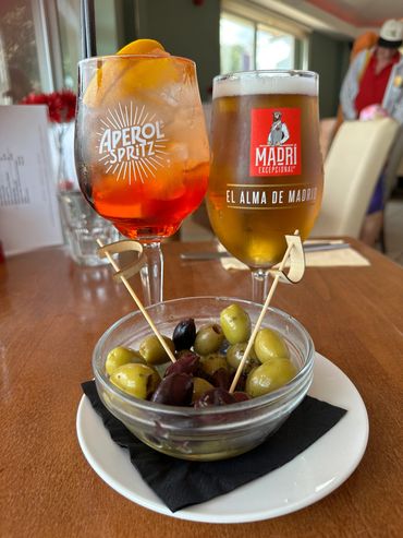 Aperol Spritz and Lager with olives on a table